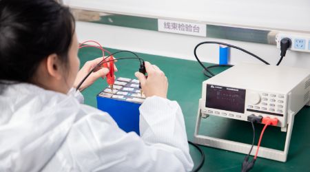The technician is holding a multimeter to check the voltage